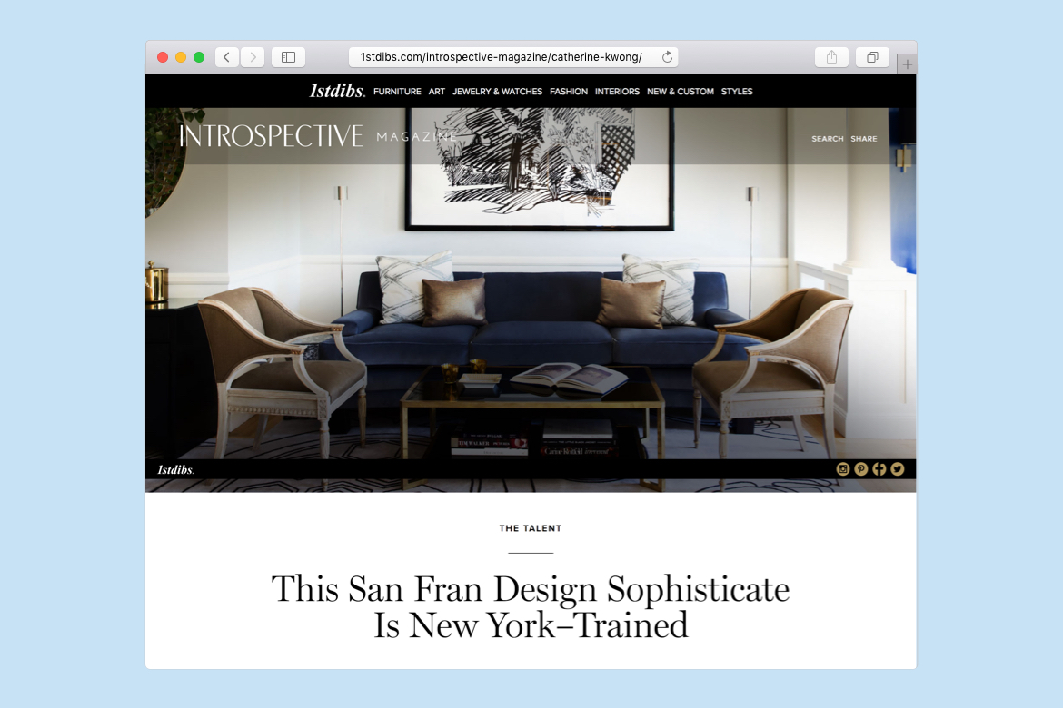 Living room with blue suede couch, black ink abstract art framed above, two single chairs with gold coffee table with books